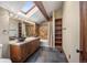 Bathroom featuring dual vessel sinks, granite countertops, a skylight, and dark wood cabinets at 12570 W 60Th Ave, Arvada, CO 80004