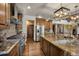 Open kitchen boasts stone accents, stainless appliances, granite counters, and center island with seating at 12570 W 60Th Ave, Arvada, CO 80004