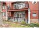 Exterior of a red brick building, featuring a balcony with a seating area and lower-level patio space at 300 Hudson St # 109, Denver, CO 80220