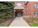 Inviting entrance with covered walkway, mature trees, and brick exterior at 300 Hudson at 300 Hudson St # 109, Denver, CO 80220