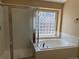 Bathroom featuring a large tub, glass block window, and chrome shower doors at 20148 E Dartmouth Dr, Aurora, CO 80013