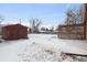 A spacious, snow-covered backyard features a storage shed and privacy lattice at 7600 Monaco St, Commerce City, CO 80022