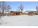 The home's backyard featuring full snow cover with a view of the house at 7600 Monaco St, Commerce City, CO 80022