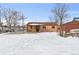 A home's brick exterior is complemented by a sprawling snowy backyard and ample storage shed at 7600 Monaco St, Commerce City, CO 80022