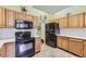 Well-maintained kitchen featuring ample wooden cabinetry and black appliances at 2265 S Depew St, Denver, CO 80227