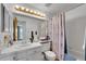 Bright bathroom featuring a vanity, mirror, and a shower-tub combination with a blue patterned curtain at 12366 Elm Way, Thornton, CO 80241
