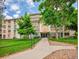 Building 210, a multi-story condo with manicured front lawn and trees under a partly cloudy sky at 3144 S Wheeling Way # 206, Aurora, CO 80014