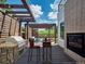 Outdoor kitchen and dining area features a built-in grill and fireplace under a wooden pergola at 6096 W Keene Ave, Denver, CO 80235