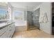 Bright bathroom featuring a glass-enclosed shower and a soaking tub under a decorative glass block window at 531 Americana Rd, Longmont, CO 80504
