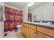 Bathroom features a double sink vanity and a shower with a colorful, patterned curtain at 531 Americana Rd, Longmont, CO 80504