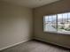 A bright bedroom has neutral carpet and a window with a view of nearby townhomes at 9578 Pearl Cir # 105, Parker, CO 80134