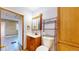 Bathroom with light walls, wood cabinets, white toilet and sink, and an organizing shelf at 598 S Navajo St, Denver, CO 80223