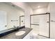 Bathroom featuring a glass shower, white cabinetry, and a large mirror at 8509 Orchard City Dr, Littleton, CO 80125