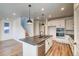 Bright, open-concept kitchen with white cabinets, stainless appliances, a large island, and wood-style floors at 8509 Orchard City Dr, Littleton, CO 80125