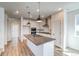 Bright, open-concept kitchen with white cabinets, stainless appliances, a large island, and wood-style floors at 8509 Orchard City Dr, Littleton, CO 80125