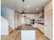 Bright, open-concept kitchen with white cabinets, stainless appliances, a large island, and wood-style floors at 8509 Orchard City Dr, Littleton, CO 80125