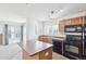 Bright kitchen with wood cabinets, black appliances, and a view of the living area at 23505 E Platte Dr # 8D, Aurora, CO 80016