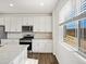Bright kitchen features white cabinets, stainless steel appliances, granite counters and view to backyard at 8850 Sedalia St, Commerce City, CO 80022