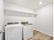 A laundry room with a washer, dryer, shelving, and wood flooring at 8850 Sedalia St, Commerce City, CO 80022