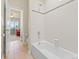 Tiled bathtub and shower featuring a tile backsplash and an adjoining room with a peek at a red sofa at 13645 Osage Ct, Broomfield, CO 80023