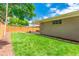 Backyard featuring a lush lawn, mature trees, wooden fence, and small patio area at 3098 S Vine St, Denver, CO 80210