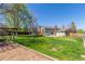 Expansive backyard with lush green grass, mature trees, playset, and a charming home exterior at 7367 Coors St, Arvada, CO 80005