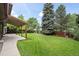 Spacious backyard with lush green grass, mature trees, and a covered patio, perfect for outdoor entertaining at 7409 Mount Meeker Rd, Longmont, CO 80503