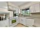 Bright kitchen featuring granite countertops, white cabinetry, and modern appliances at 12355 E Arkansas Pl, Aurora, CO 80012