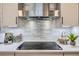 Updated kitchen features stainless steel range hood, cooktop, tile backsplash, and stylish decor at 7998 S Wabash Ct, Centennial, CO 80112