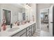 Bathroom featuring double sinks, a large mirror, and a view into another room with natural light at 3091 Keepsake Way, Castle Rock, CO 80109