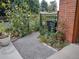 Charming side yard featuring a garden with sunflowers, a gravel pathway, and blooming foliage near the brick house at 2700 S High St, Denver, CO 80210