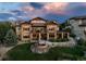 Aerial view of the back exterior of the home shows the multi-level deck, stone accents and backyard fire pit at 10783 Backcountry Dr, Highlands Ranch, CO 80126