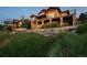 The exterior of the home includes a rock retaining wall, lush green lawn and two-story deck at sunset at 10783 Backcountry Dr, Highlands Ranch, CO 80126