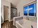Bright bathroom featuring a soaking tub, walk-in shower, and a large window with a view at 2010 Saddleback Dr, Castle Rock, CO 80104
