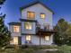 Two-story home's rear exterior featuring a deck, backyard, and illuminated windows at 2010 Saddleback Dr, Castle Rock, CO 80104