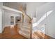 Elegant foyer with a curved staircase, light wood floors, and a view of the living spaces beyond at 5191 S Hannibal Way, Centennial, CO 80015