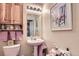 Charming bathroom with pedestal sink, decorative wallpaper border, and wall-mounted storage at 12835 Mayfair Way # C, Englewood, CO 80112
