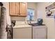 Bright laundry room with wooden cabinets, washer, dryer, and a window bringing in natural light at 12835 Mayfair Way # C, Englewood, CO 80112