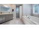 Well-lit bathroom features a soaking tub, double vanity, and skylight, combining luxury and functionality at 6650 Village Rd, Parker, CO 80134