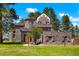 Stunning castle home with stone exterior, arched windows, and mature trees on a lush green lawn at 6650 Village Rd, Parker, CO 80134