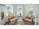 Light-filled sunroom with two chairs, two windows, and a decorative table with scenic views at 6650 Village Rd, Parker, CO 80134