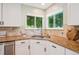 Bright kitchen featuring granite counters, white cabinets, stainless steel sink and two windows looking out to the yard at 10096 Hughes Pl, Highlands Ranch, CO 80126