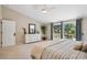 Bright main bedroom with access to a balcony, large windows, light carpet, and views of the forest at 10096 Hughes Pl, Highlands Ranch, CO 80126