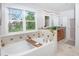 Luxurious bathroom featuring a soaking tub, dual vanities, and ample natural light from the window at 902 Grove Dr, Louisville, CO 80027