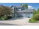 Two car garage with an American flag hanging in the middle of the two doors and mature landscaping around the driveway at 902 Grove Dr, Louisville, CO 80027