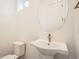 Stylish half bathroom features a round mirror, white pedestal sink, and modern gold faucet at 918 Promenade Dr, Superior, CO 80027