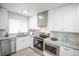 Well-lit kitchen featuring stainless steel appliances, white cabinets, and granite countertops at 1150 S Taos Way, Denver, CO 80223