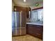 Modern kitchen with stainless steel refrigerator, granite countertops, and dark wood cabinets at 11257 W Radcliffe Dr, Littleton, CO 80127
