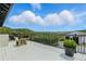 Expansive backyard deck with comfortable seating and panoramic views of the lush green landscape and distant buildings at 1140 Lake Gulch Rd, Castle Rock, CO 80104