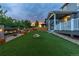 Beautiful backyard at dusk featuring a rock fire pit, artificial grass, planter boxes, and string lights for ambiance at 1315 Sidewinder Cir, Castle Rock, CO 80108